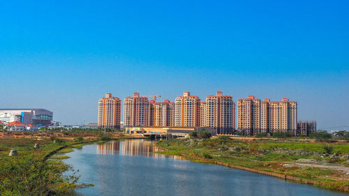 Buildings by river against blue sky