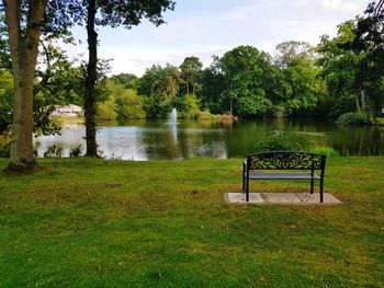 Scenic view of lake by trees on field against sky