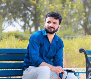 Young man sitting on bench in park