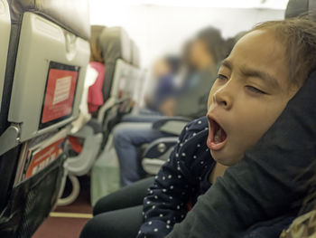 Close-up of cute girl yawning in airplane