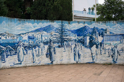 Graffiti on wall by trees and buildings in city