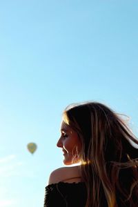 Young woman by hot air balloon against clear sky