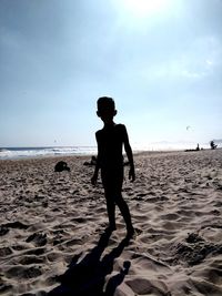 Portrait of boy standing at shore of beach against sky