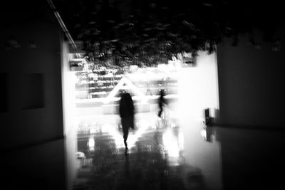 Silhouette people walking on building seen through window