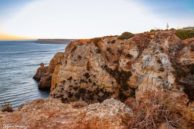 Rock formations by sea against sky