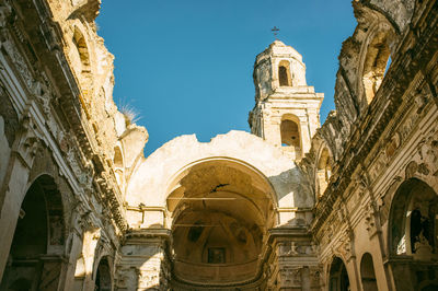 Low angle view of damaged cathedral against clear blue sky at bussana vecchia