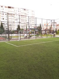 View of soccer field by buildings against sky