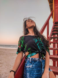 Beautiful woman standing at beach against sky