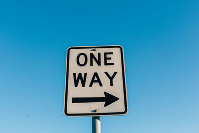 Low angle view of road sign against blue sky