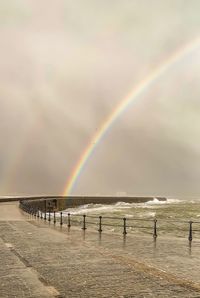 Scenic view of beach against rainbow in sky