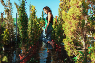 Full length of woman standing by lake in forest