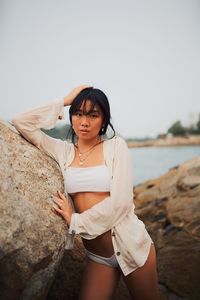 Portrait of sensuous young woman wearing bikini standing at beach