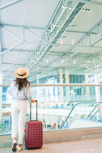 Rear view of woman with suitcase standing at airport