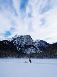 People riding horse on snowcapped mountain against sky