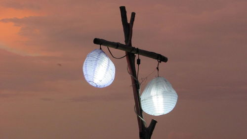 Low angle view of illuminated light bulb against sky during sunset