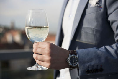 Midsection of businessman holding wine in glass