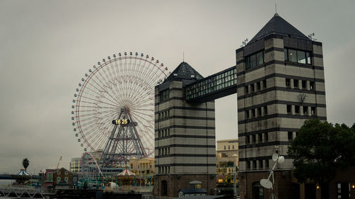 Low angle view of ferris wheel against buildings