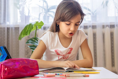 Girl drawing on book at home