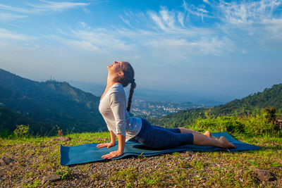 Woman practices yoga asana urdhva mukha svanasana outdoors