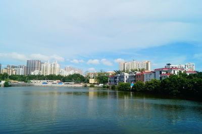 Buildings by river against sky in city