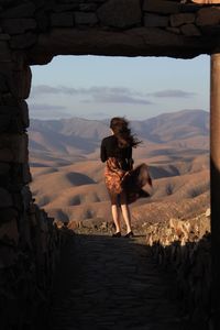 Woman standing on rock against sky