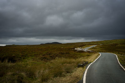 Road on field against cloudy sky