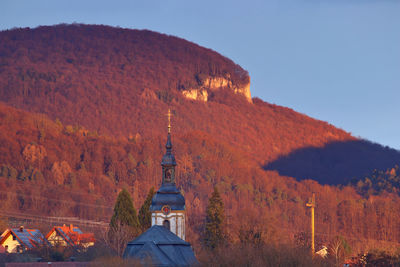 Scenic steeple against hill with rocks in sunlight