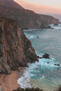 Scenic view of sea by mountain against sky