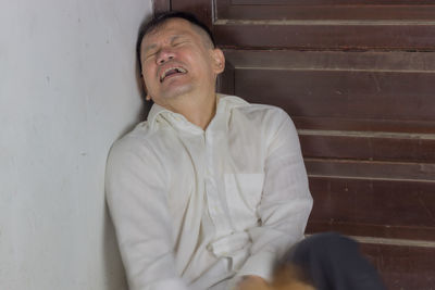 Midsection of young man sitting against wall