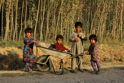 Full length portrait of children standing against trees