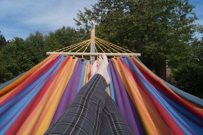 Low section of woman relaxing on hammock against trees