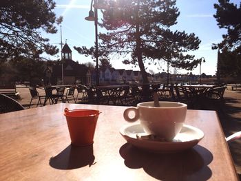 Close-up of coffee on table by trees against sky