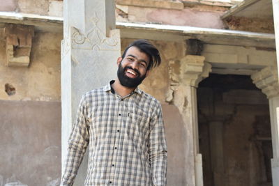 Smiling young man standing against historic building