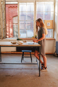 Side view of woman sitting on table at home