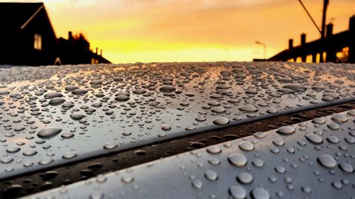 Close-up of wet car against sky during sunset