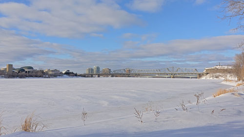 Snow covered field by buildings against sky