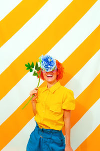 Smile woman on trend striped yellow background with flower in her hands. minimal 