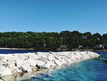 Rocks by swimming pool against clear blue sky