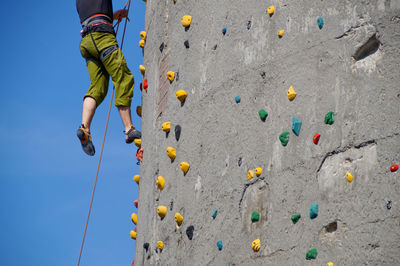 Low angle view of man climbing wall against sky