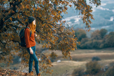 Woman standing by tree during autumn