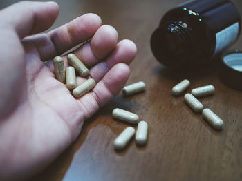 Close-up of hand holding capsules on table 