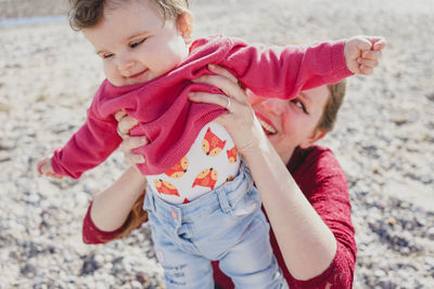 Mother holding while playing with daughter at beach