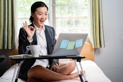 Young woman using mobile phone while sitting on table