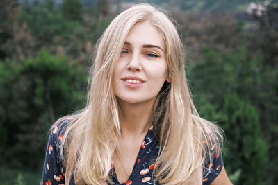 Portrait of a young attractive blue-eyed blonde woman with long hair looking at camera and smiling