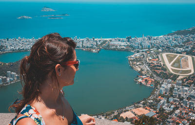 Woman wearing sunglasses by sea in city