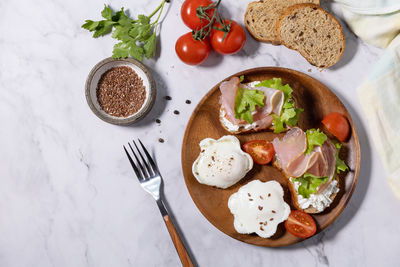 Delicious breakfast or snack - poached egg and cream cheese toast whole grain rye bread, prosciutto