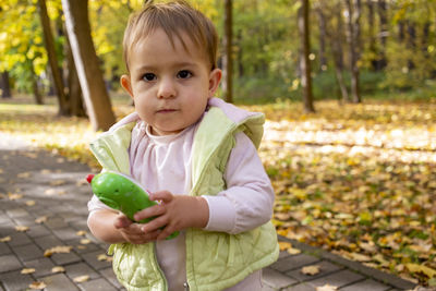 Cute serious toddler baby holding a toy phone in the park