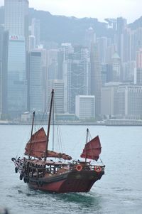 Sailboats in river by buildings in city
