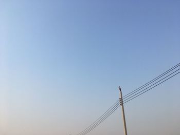 Low angle view of electricity pylon against clear sky