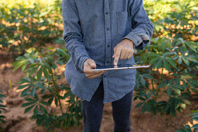 Midsection of man holding umbrella standing on field